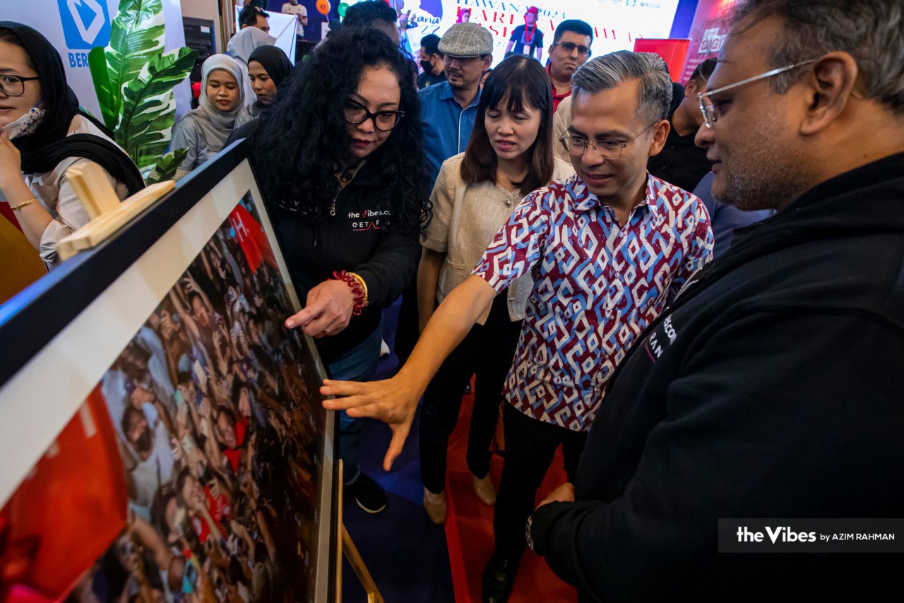 Kehadiran Fahmi dan Nie Ching ke gerai pameran The Vibes dan Getaran disambut oleh  Ketua Pengarang Petra News merangkap Pengarang Urusan The Vibes, Terence Fernandez (kanan).