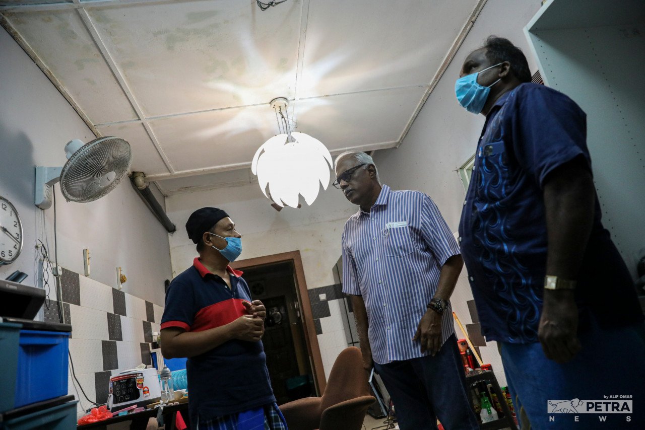 Zainuddin (kiri) berbual dengan Charles Santiago (tengah) mengenai keadaan rumahnya selepas banjir. - Gambar oleh Alif Omar 