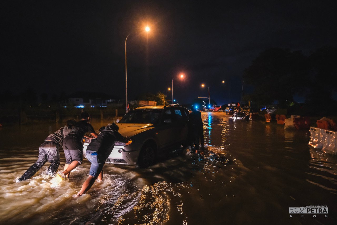 Penduduk setempat membantu menolak sebuah kereta yang terperangkap di dalam banjir di Jalan Bukit Minyak, Bukit Mertajam, Khamis lalu.