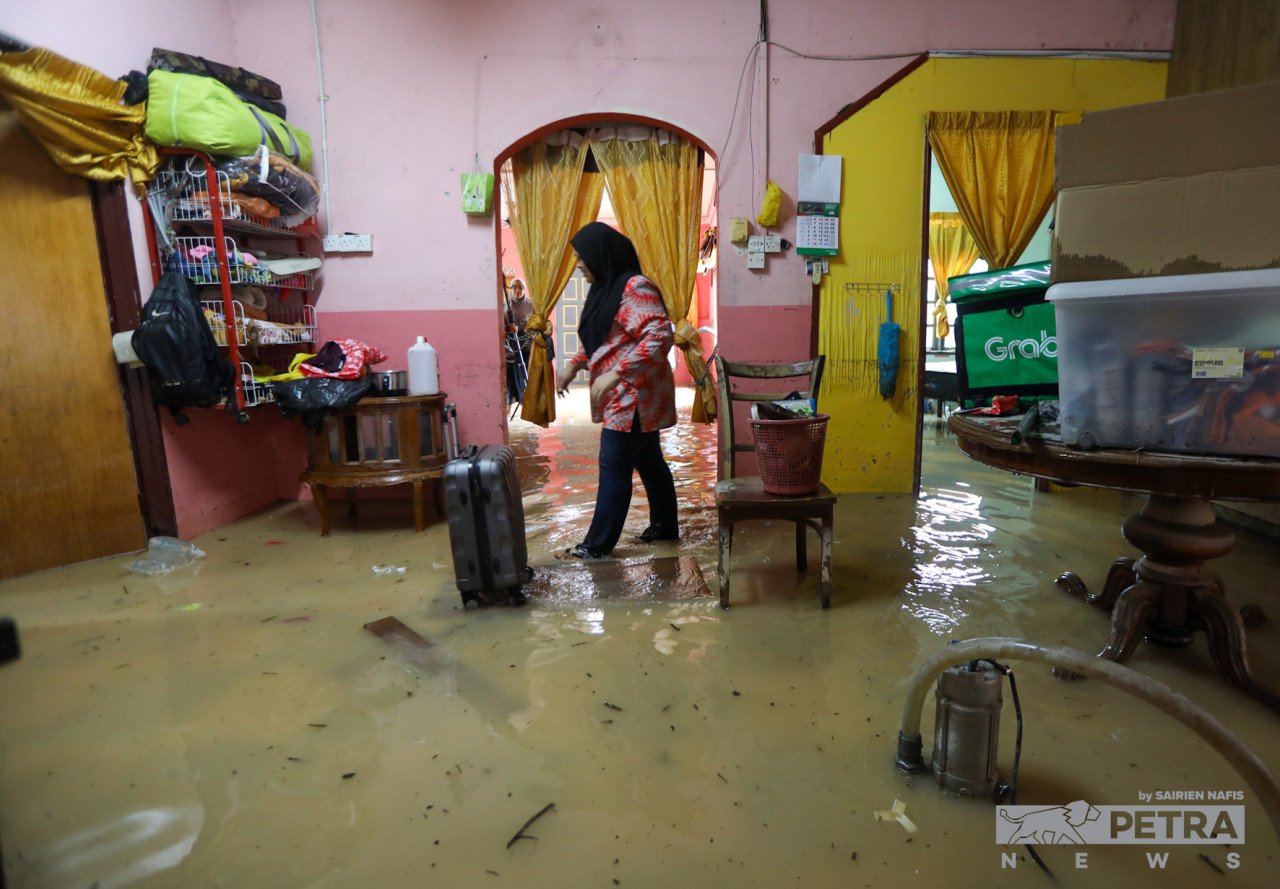 Seorang wanita meninjau keadaan dalam rumahnya yang dinaiki air di Kampung Budiman, Klang, Khamis lalu.