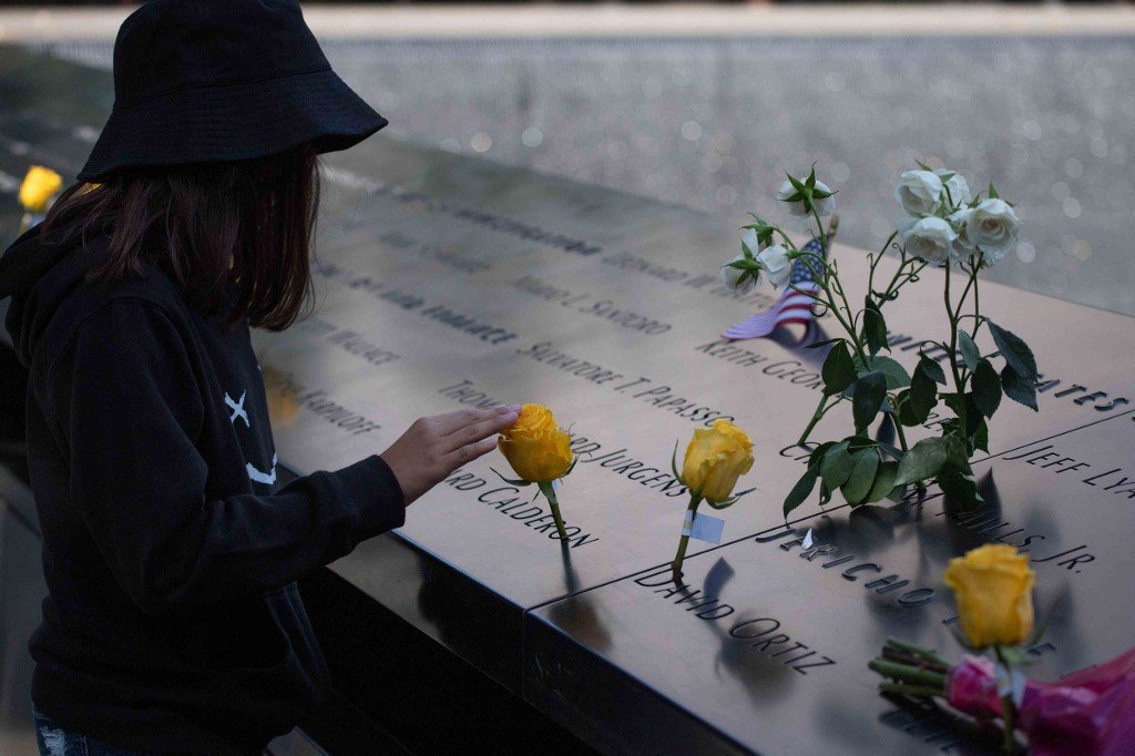 Seorang gadis memegang bunga ros ketika melawat National 9/11 Memorial and Museum di New York pada ulang tahun ke-20, tragedi 11 September 2001. - Gambar AFP