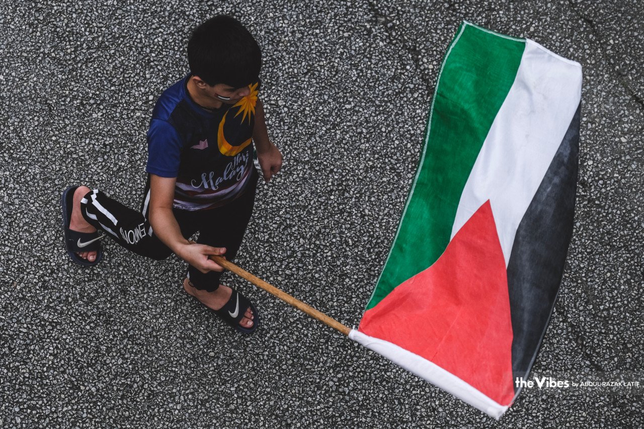Kanak-kanak lelaki ini bersemangat mengibarkan bendera Palestin sambil berarak menuju ke Kedutaan Amerika Syarikat