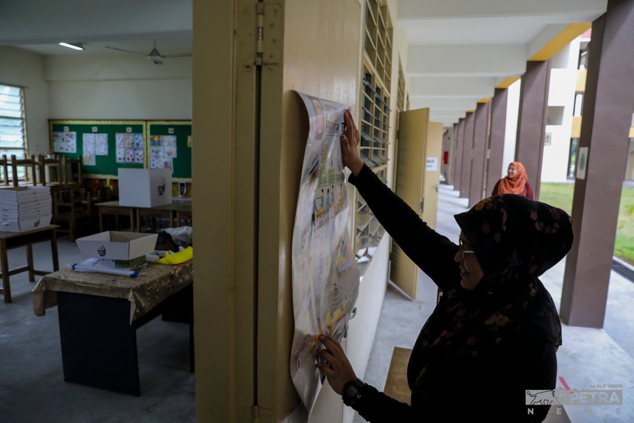 Petugas SPR melekatkan panduan mengundi di Pusat Mengundi Sekolah Kebangsaan Meru Jaya.
