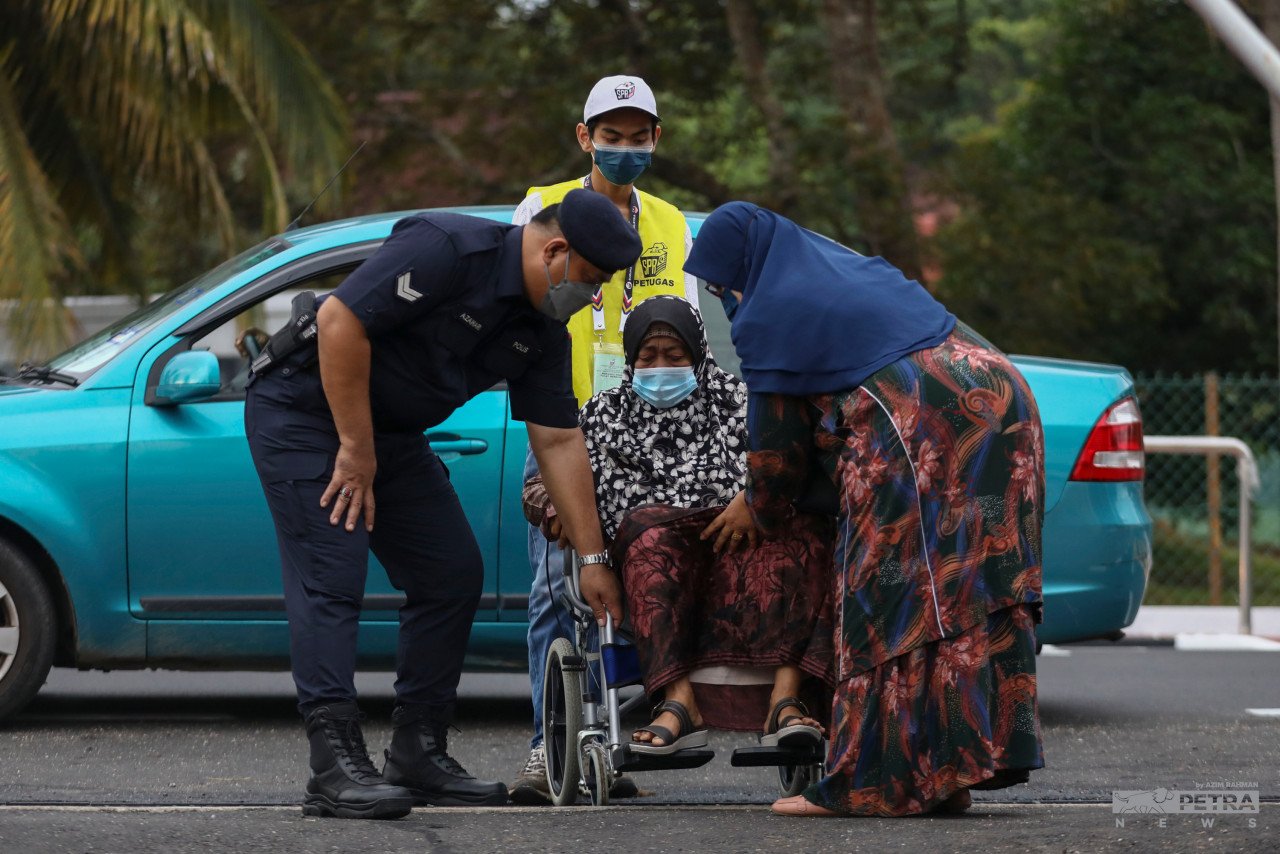 Seorang warga emas dibantu oleh petugas hari pengundian untuk membuang undi di SK Durian Daun. - Gambar Azim Abd Rahman