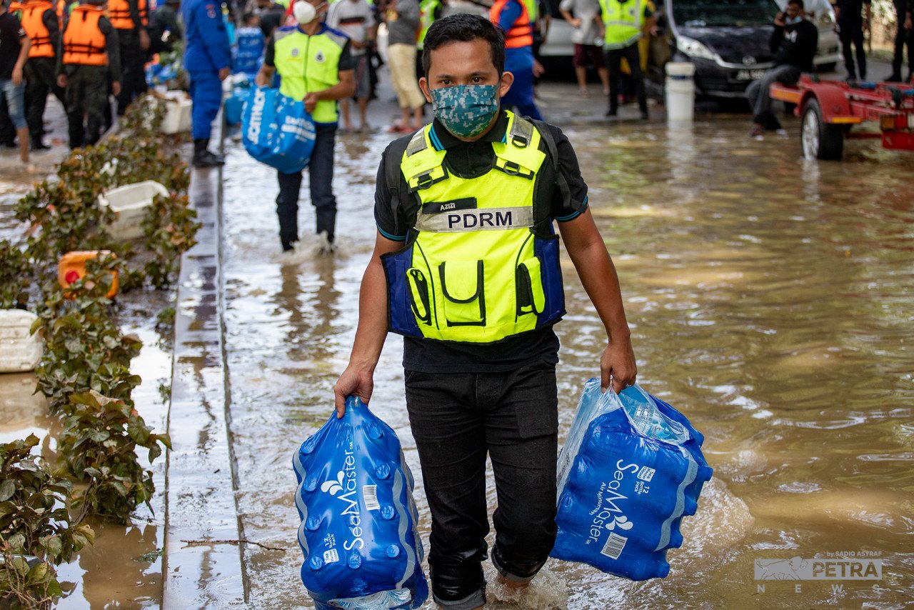 Seorang anggota polis membawa botol air mineral untuk dibekalkan kepada petugas keselamatan dan mangsa banjir.