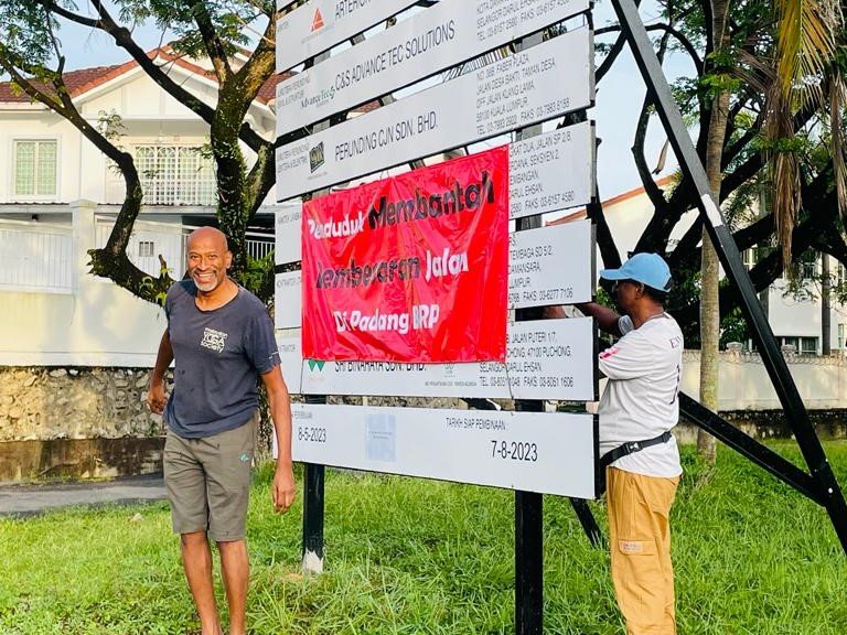 Ahli Save Padang BRP menaikkan kain rentang bantahan penduduk di atas papan tanda projek terbabit. - Gambar ihsan Kumpulan Save Padang BRP