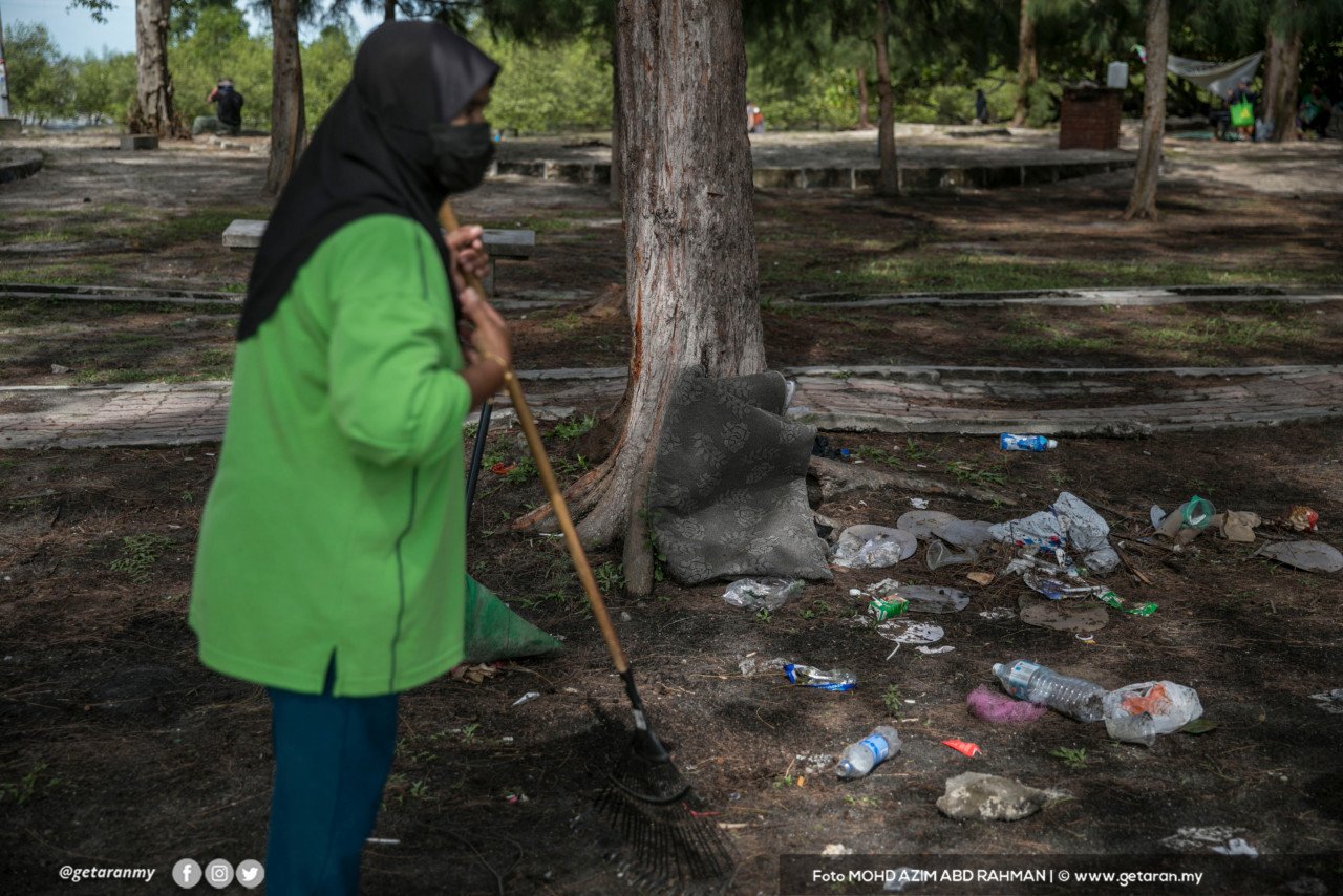 Seorang pekerja pembersihan sedang menyapu sampah sarap yang ditinggalkan pengunjung di Pantai Morib, Selangor.