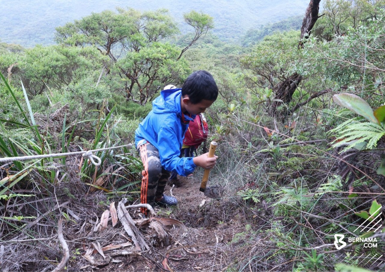 Anas Ahmad menggunakan cangkul kecilnya untuk membina laluan mendaki di lereng gunung.