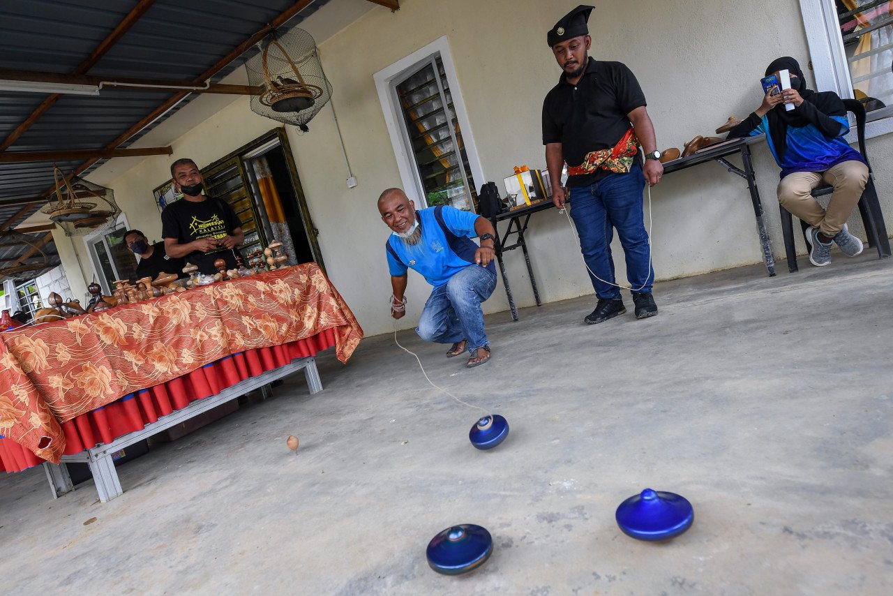 Zulkarin menunjukkan cara melempar gasing ketika kunjungan media ke Felda Kampung Tenang.