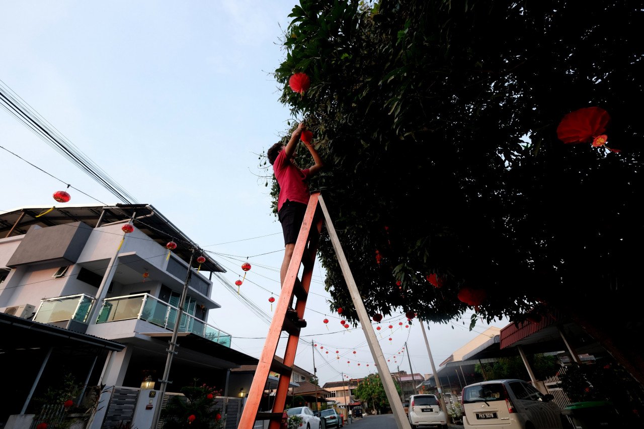 Kelihatan Lim Thean Wei, 33, menghiasi sebatang pokok di taman mereka ketika tinjauan