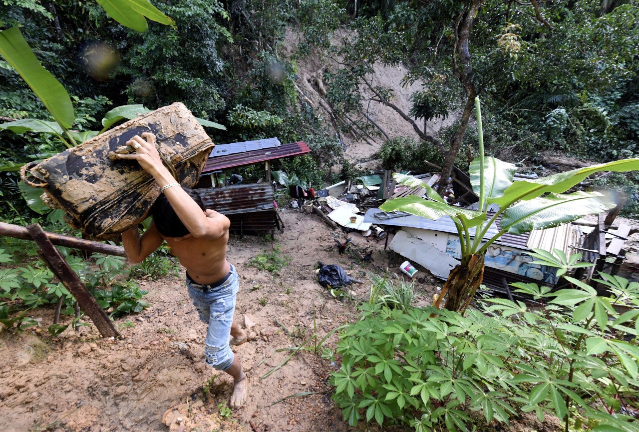 Seorang penduduk Bukit Nenas membantu mengeluarkan barangan dari sebuah rumah yang musnah dalam kejadian tanah runtuh di Taman Elok, Jalan Bukit Nenas, Kota Kinabalu - Gambar Bernama