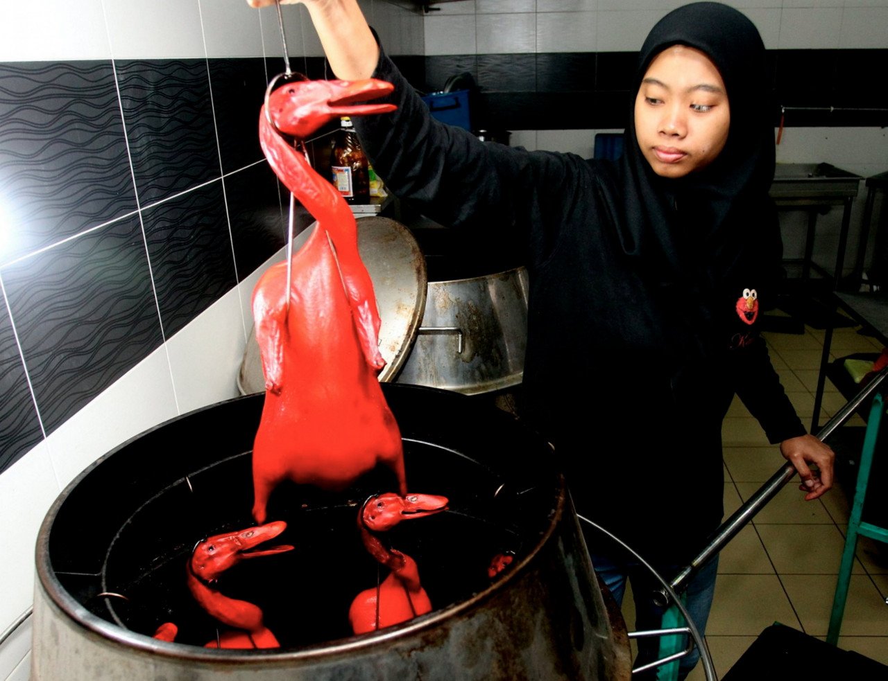 Pekerja Hidayah Azahar, 23, memasukkan beberapa ekor itik ke dalam pemanggang. - Gambar Bernama