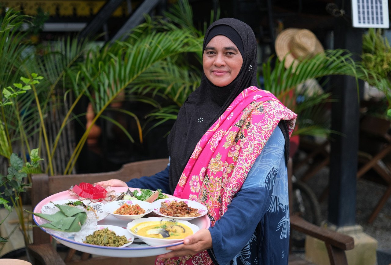 Pemilik Rumah Atap Kuning, Zaida Mohamed Abdul Aziz, menunjukkan juadah masakan kampung yang ditawarkan kepada pelanggan. – gambar BERNAMA