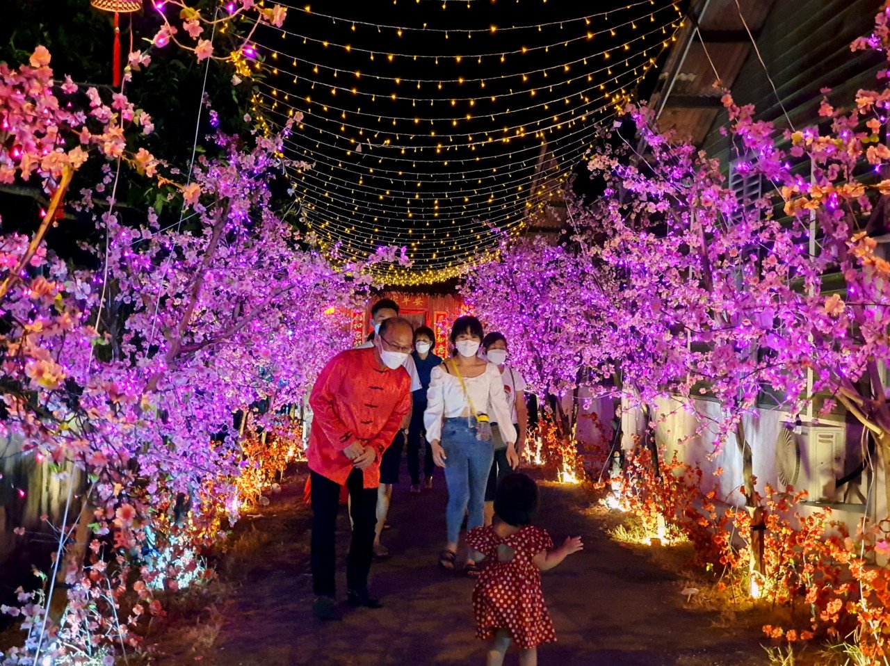 Ngwe Hee Sem (kiri) bersama pengunjung di Meihua Walk di Kampung Machap Baru yang dihiasai dengan pelbagai lampu sempena sambutan Tahun Baru Cina.
