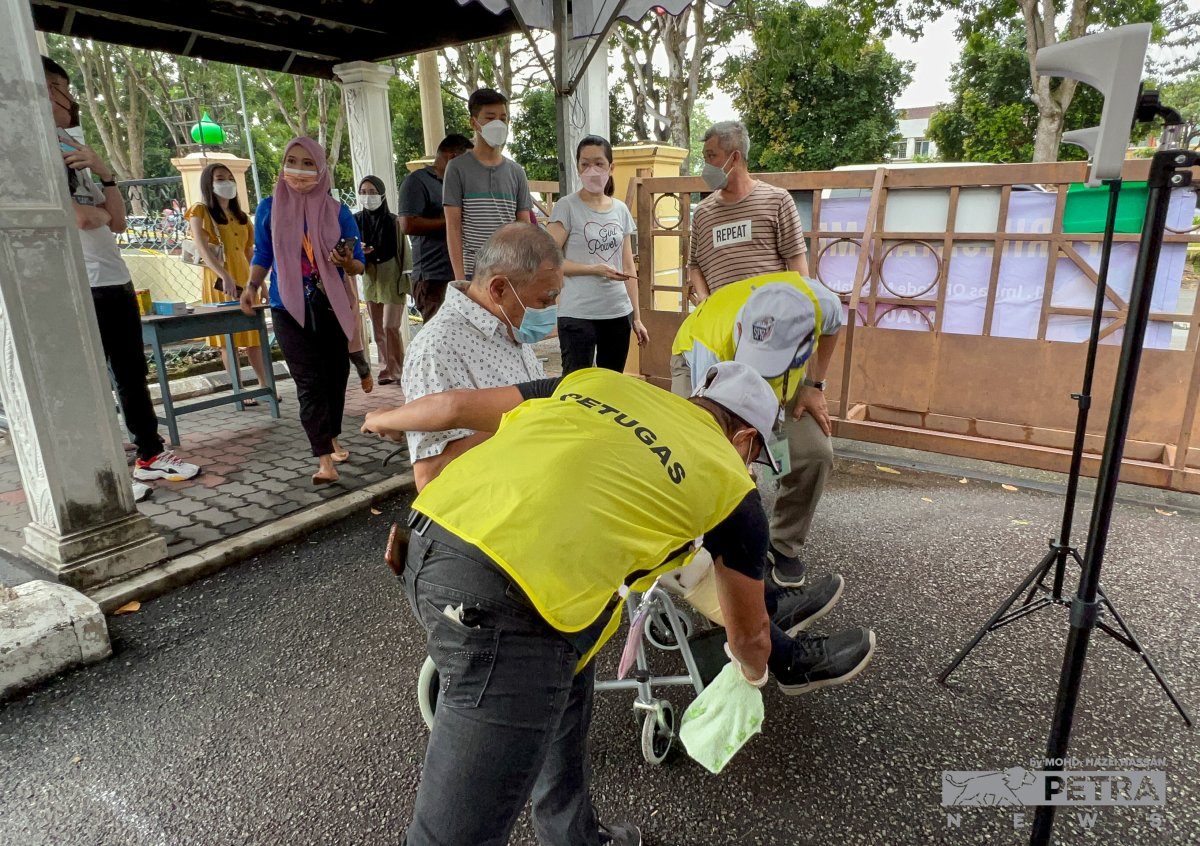 Seorang petugas SPR membantu seorang warga emas untuk mengundi di PDM Sekolah Rendah Agama JAIM, Taman Datuk Tamby Chik Karim. - Gambar Hazli Hassan