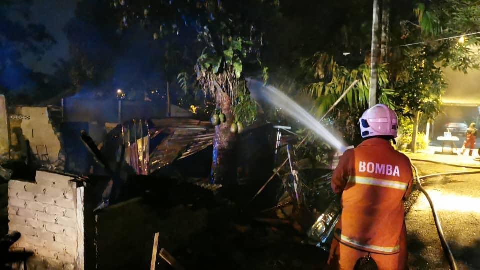 Seorang anggota bomba memadamkan kebakaran melibatkan tiga buah rumah di Kampung Padang Tembak, malam tadi.