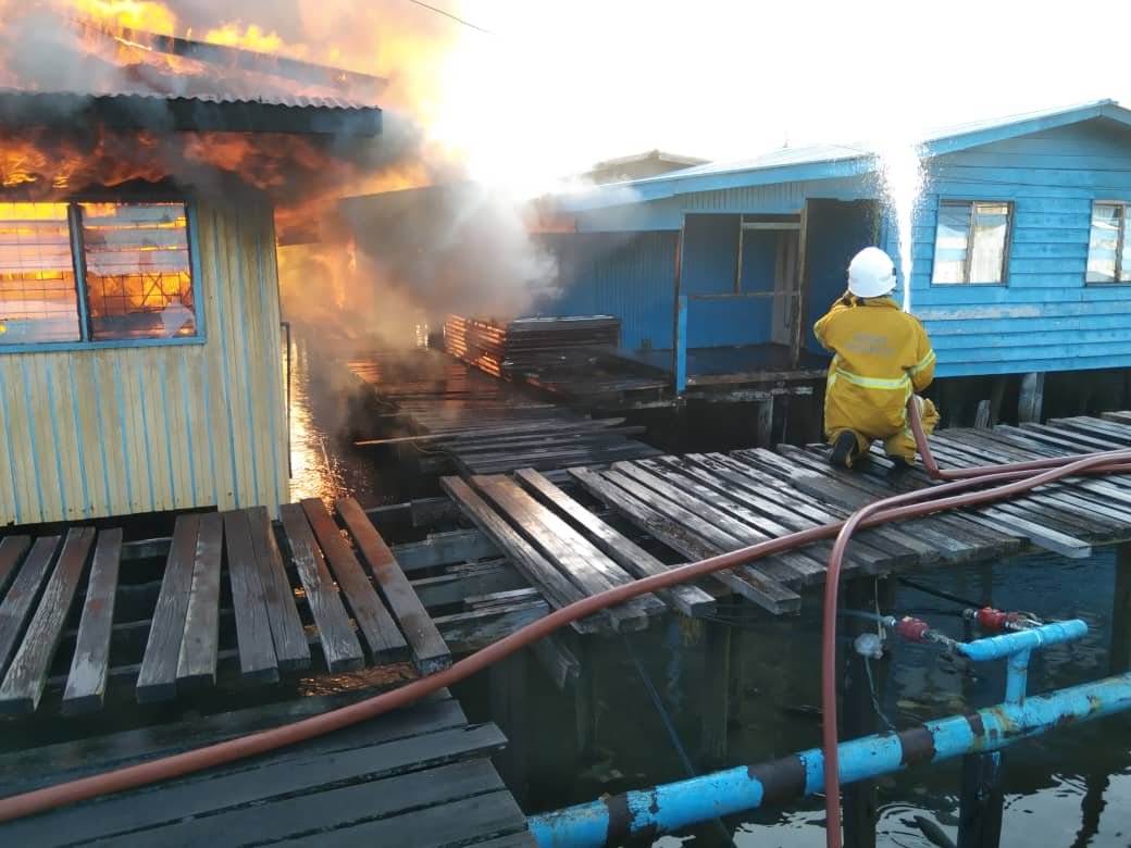 Seorang anggota bomba cuba memadamkan kebakaran di Kampung Landung Ayang Laut, semalam. - Gambar ihsan JBPM