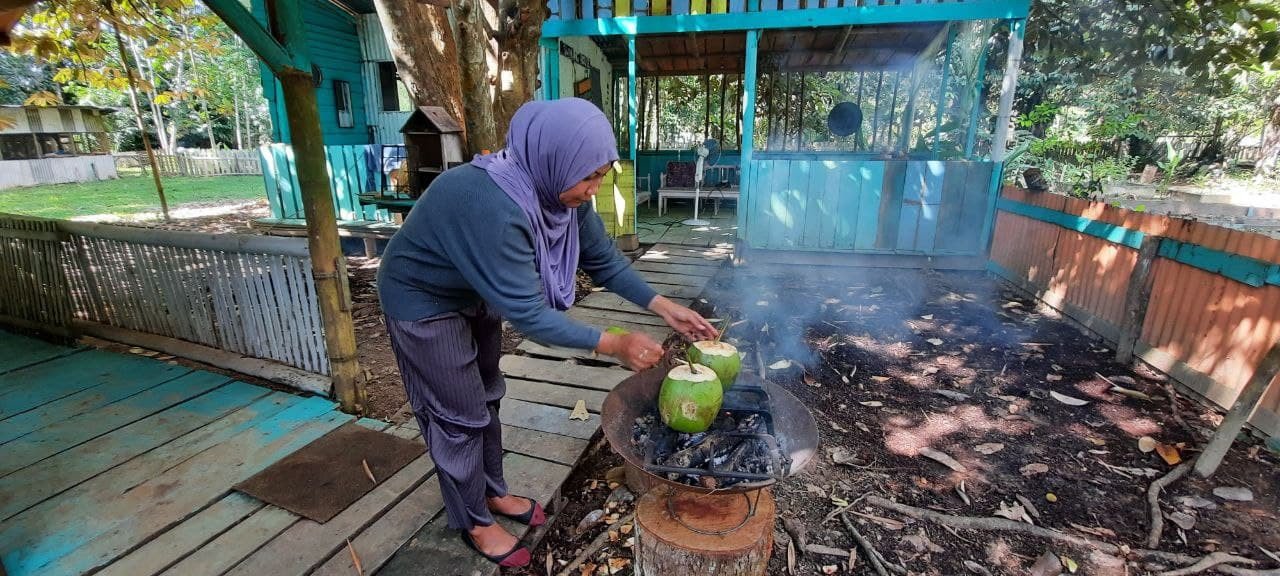 Dayang Rohani membakar kelapa bersama Serai Aceh. Semua bahan didapati dari kebun