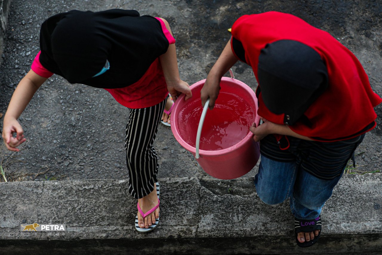 Dua kanak-kanak membawa air di dalam baldi di Shah Alam.