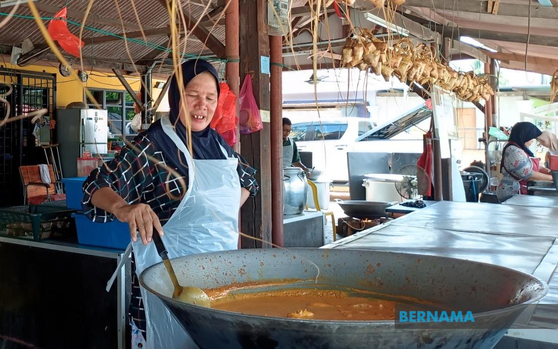Pekerja memasak rendang bagi dimakan dengan ketupat yang dijual di gerai Ketupat Mohd Zaim. - gambar BERNAMA