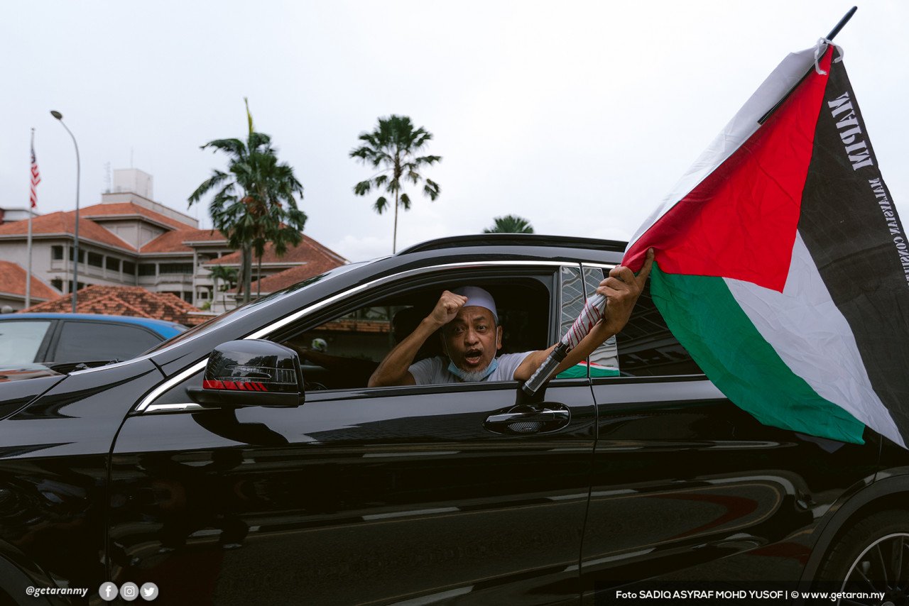 Seorang anggota NGO mengibarkan bendera Palestin ketika melalui bangunan kedutaan Amerika Syarikat di Kuala Lumpur.