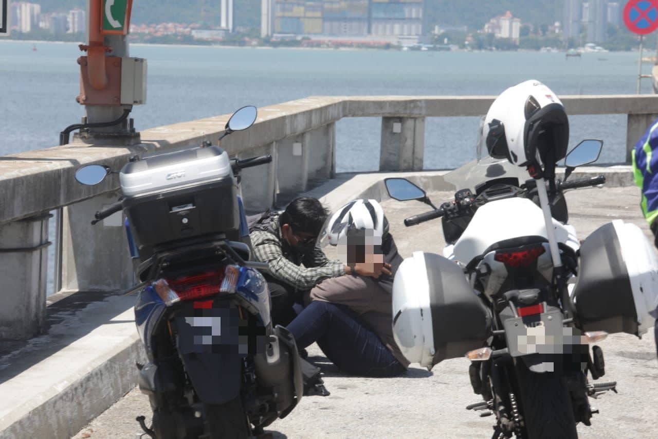 Ahmad Zhafaran cuba menenangkan seorang wanita yang cuba terjun dari Jambatan Pulau Pinang, hari ini. - Gambar Masry Che Ani
