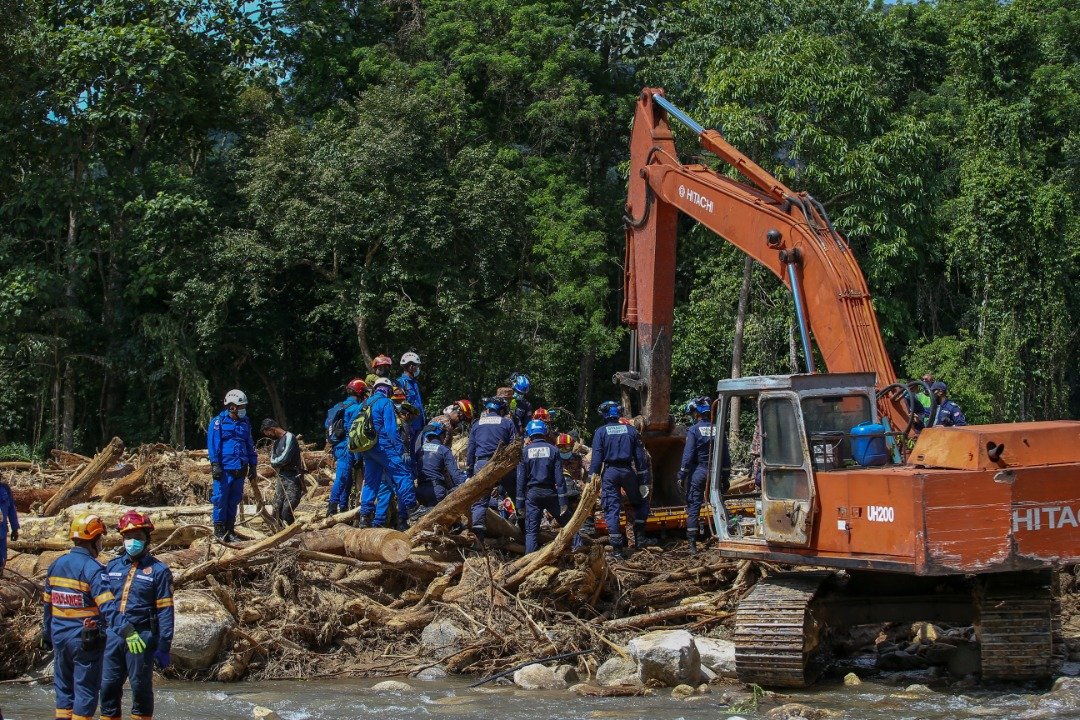 Pasukan penyelamat menggunakan jentera bagi mengalihkan timbunan kayu di lokasi jasad bekas imam, Ku Shuib Ku Abdullah ditemui