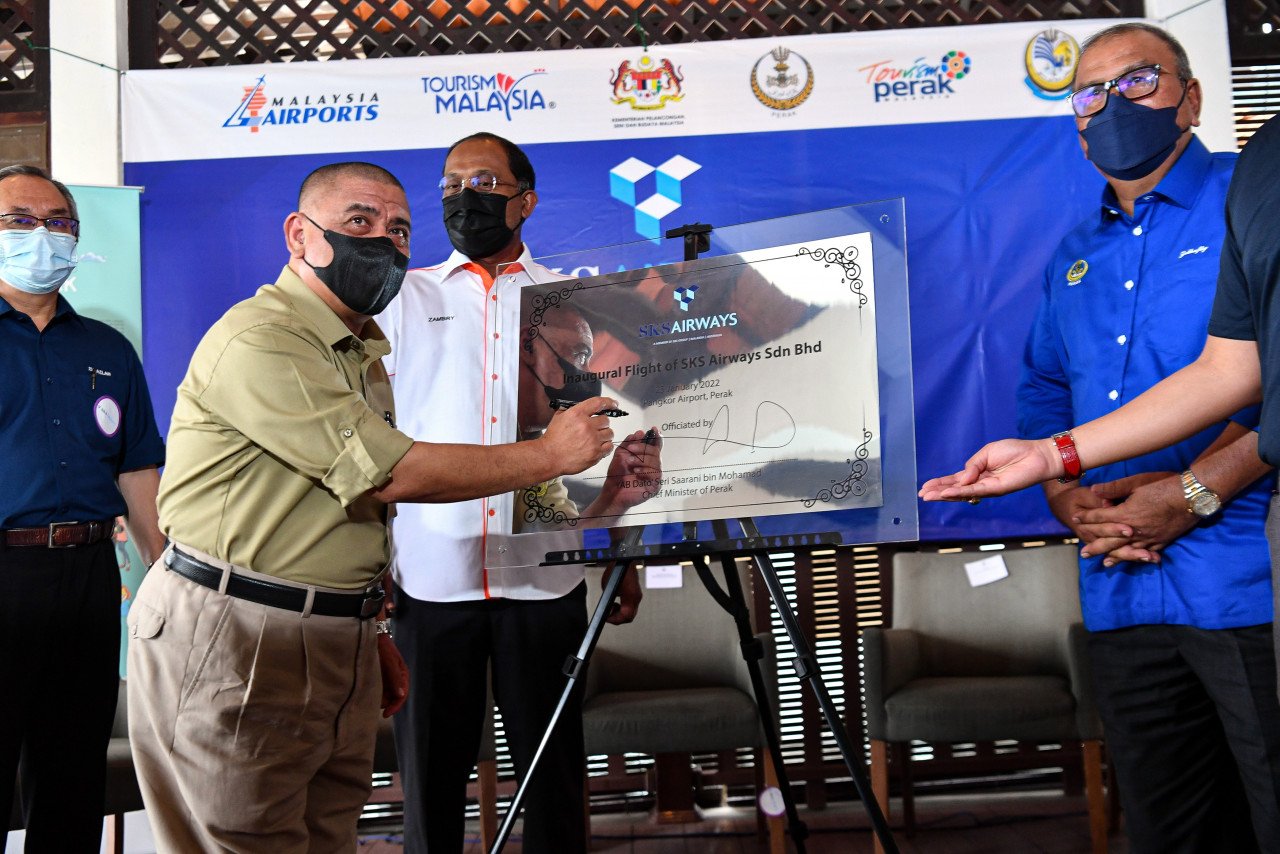  Saarani (dua, kiri) menandatangani plak pada gimik perasmian Sambutan Penerbangan 'SKS Airways Subang-Pangkor' di Lapangan Terbang Pangkor.