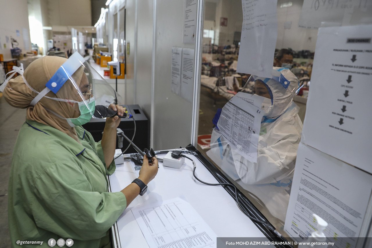 Seorang petugas perubatan menyampaikan sesuatu menerusi pembesar suara kepada pesakit COVID-19 kategori 3 yang sedang menjalani kuarantin di PKRC di MAEPS, Serdang.