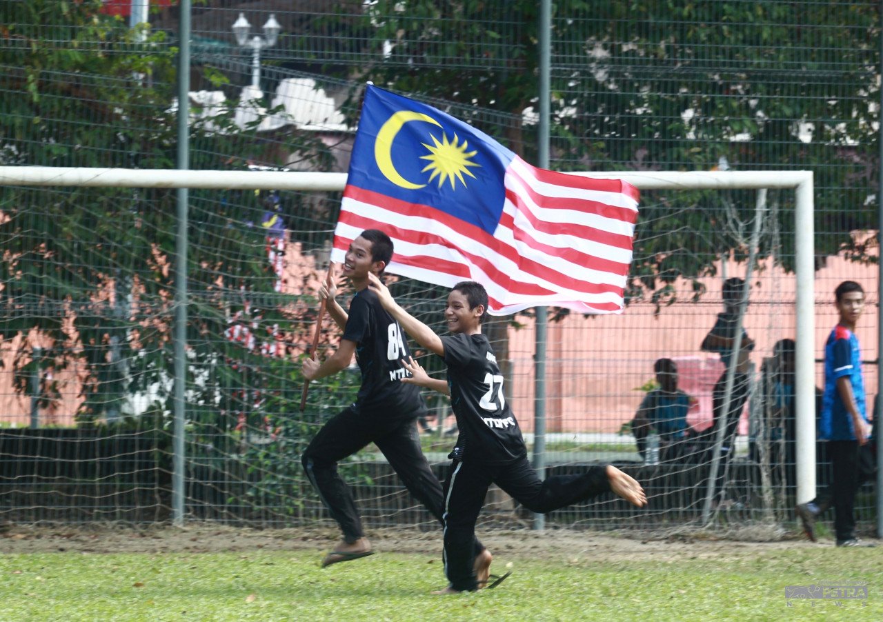 Kanak-kanak mengibarkan Jalur Gemilang selepas bermain bola sepak di Kg Baru Kuala Lumpur. gambar Azlan Hadi Abu Bakar
