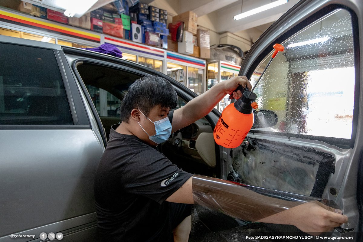 Seorang pekerja kedai cermin kereta menyiapkan kenderaan yang dihantar oleh pelanggan, sehari sebelum sekatan pergerakan penuh dilaksanakan.