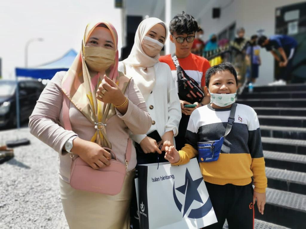 Siti Saniyah (kiri) bersama 3 anaknya yang datang dari Puchong tidak kisah untuk beratur selama sejam bagi mendapatkan kelengkapan raya di Bulan Bintang di Bangi Sentral, Bangi.