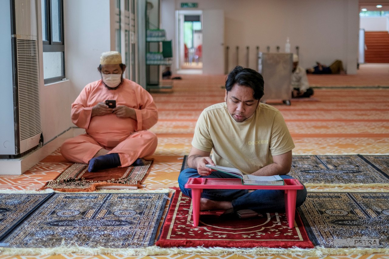 Beberapa jemaah mengambil peluang membaca Al-Quran bagi mengisi masa sebelum menunggu waktu berbuka. - Gambar oleh Abdul Razak Latif