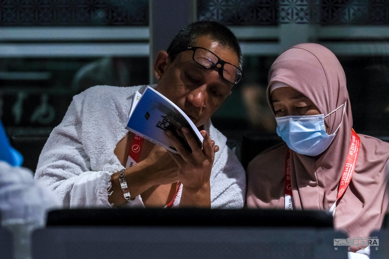 Jemaah haji membaca dan menyemak panduan menunaikan ibadah haji sementara menunggu waktu berlepas ke Jeddah. - Gambar oleh Abd Razak Latif