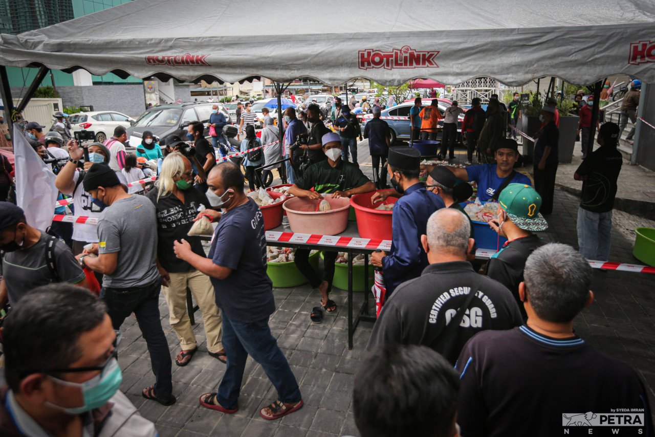 Orang ramai beratur menunggu giliran untuk menerima bubur lambuk. - Gambar oleh Syeda Imran