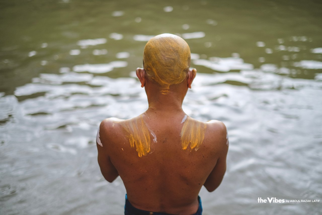 Seorang penganut Hindu melumurkan badannya dengan kunyit sambil melakukan ritual keagamaan di Sungai Tua sempena perayaan Thaipusam hari ini