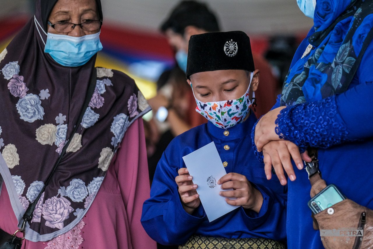 Seorang kanak-kanak lelaki menerima duit raya di Majlis Rumah Terbuka Hari Raya Aidilfitri Perdana Menteri dan Jemaah Menteri 2022 di Laman Sari, Kompleks Seri Perdana, Putrajaya. - Gambar oleh Abdul Razak Latif