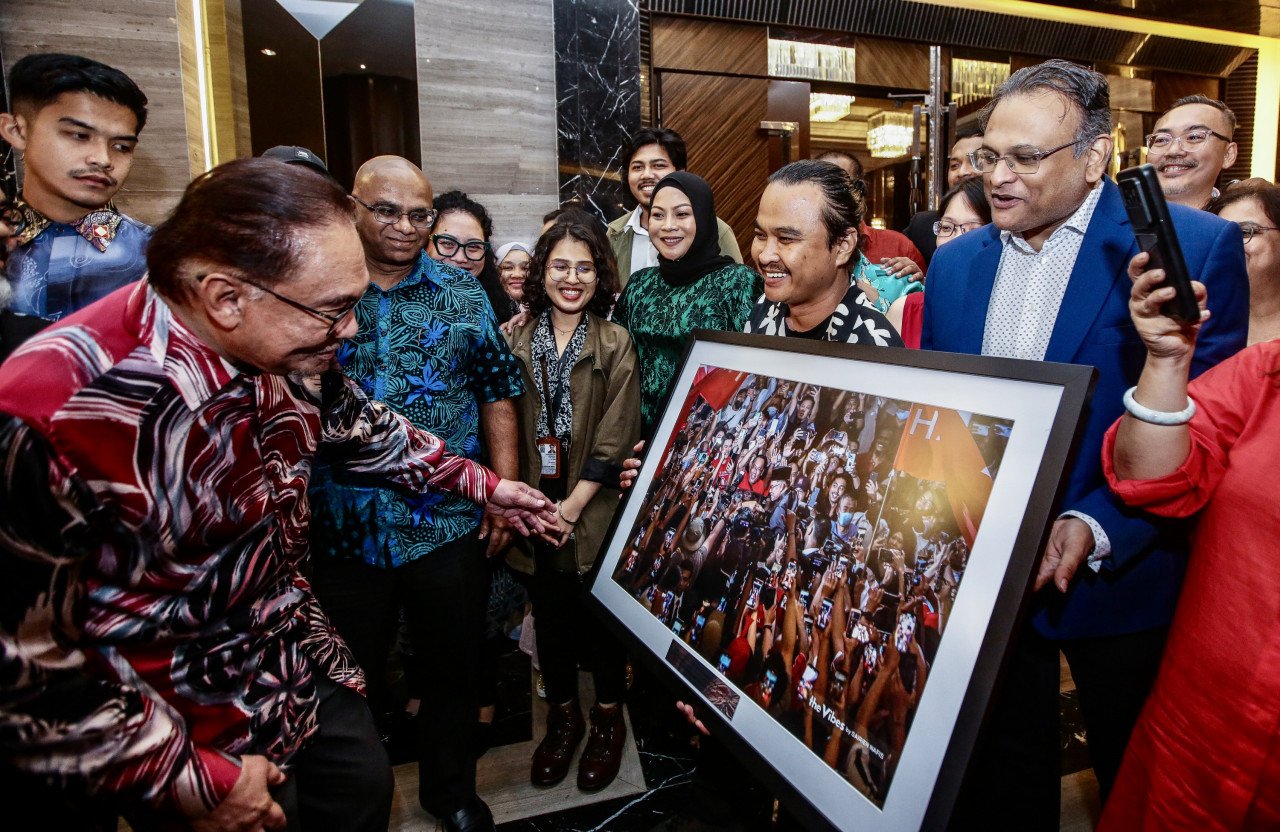 Anwar Ibrahim melihat foto hasil bidikan Sairien Nafis yang memenangi Hadiah Kewartawanan Malaysia-MPI Petronas 2022 bagi kategori Kewartawanan Foto Cemerlang