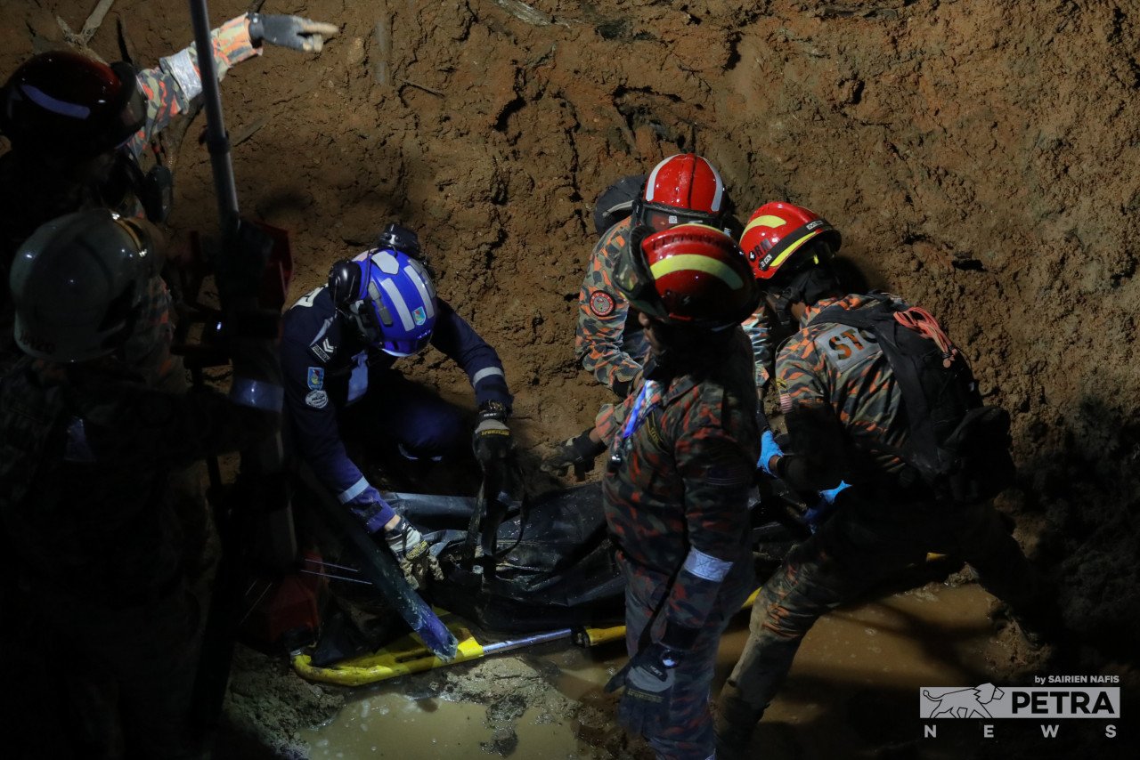 Anggota penyelamat tanah runtuh Batang Kali meletakkan mayat mangsa ke-25 tragedi itu di dalam beg mayat. Mayat kanak-kanak perempuan itu ditemui tertimbus 16m dalam lumpur. - Gambar oleh Sairien Nafis