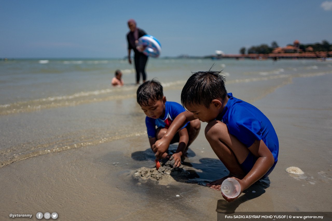 Dua orang kanak-kanak leka bermain pasir di Pantai Saujana Port Dickson. - Gambar oleh Sadiq Asyraf