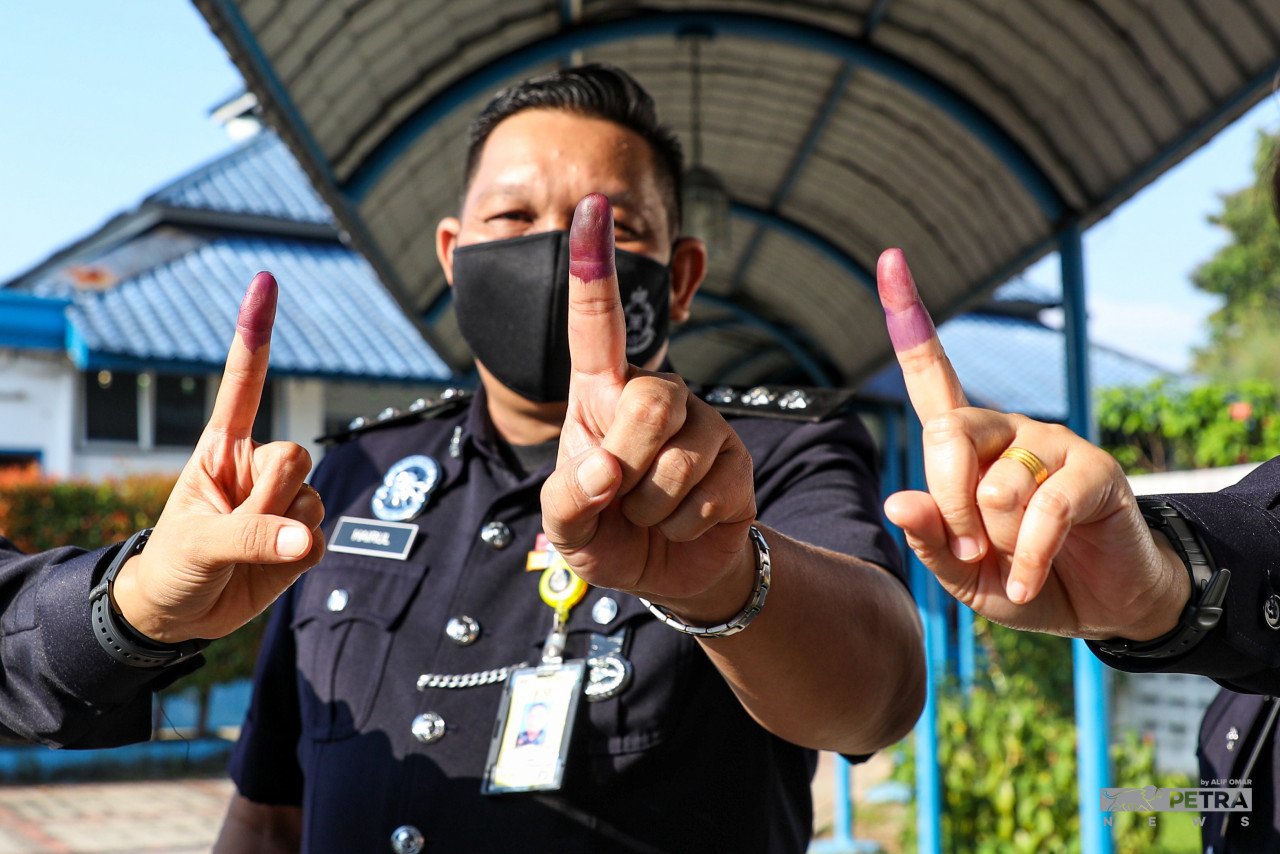 Anggota polis yang telah selesai mengundi menunjukkan jari yang disapu dakwat kekal. - Gambar oleh Alif Omar