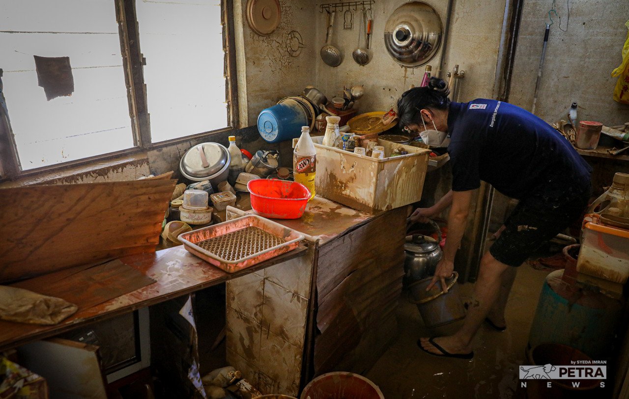 Seorang penduduk sudah 30 tahun mendiami rumah di perumahan Taman Sri Nanding sedang mengemas dapur yang dipenuhi lumpur akibat banjir semalam. - Gambar oleh Syeda Imran