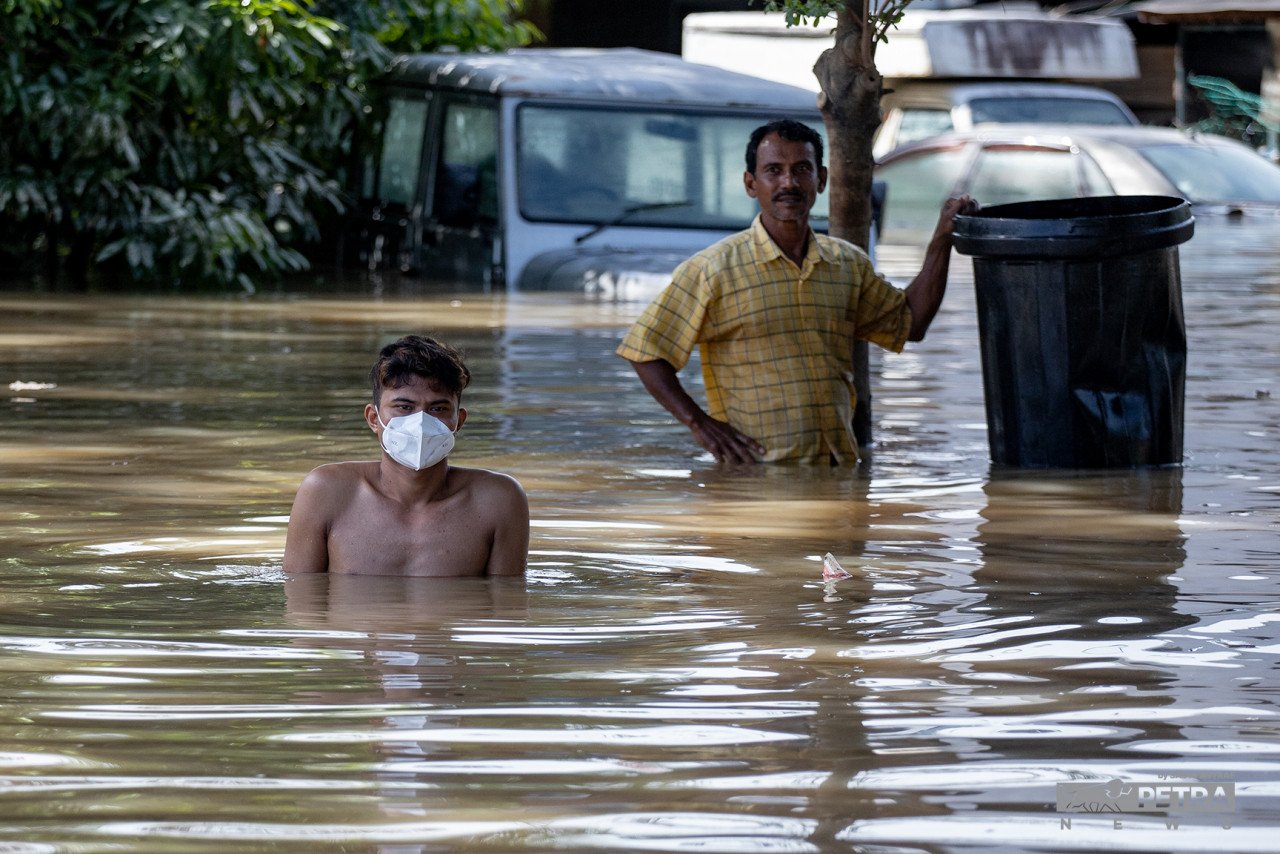 Seorang lelaki meredah air banjir di Taman Sri Muda. - Gambar oleh Sadiq Asyraf