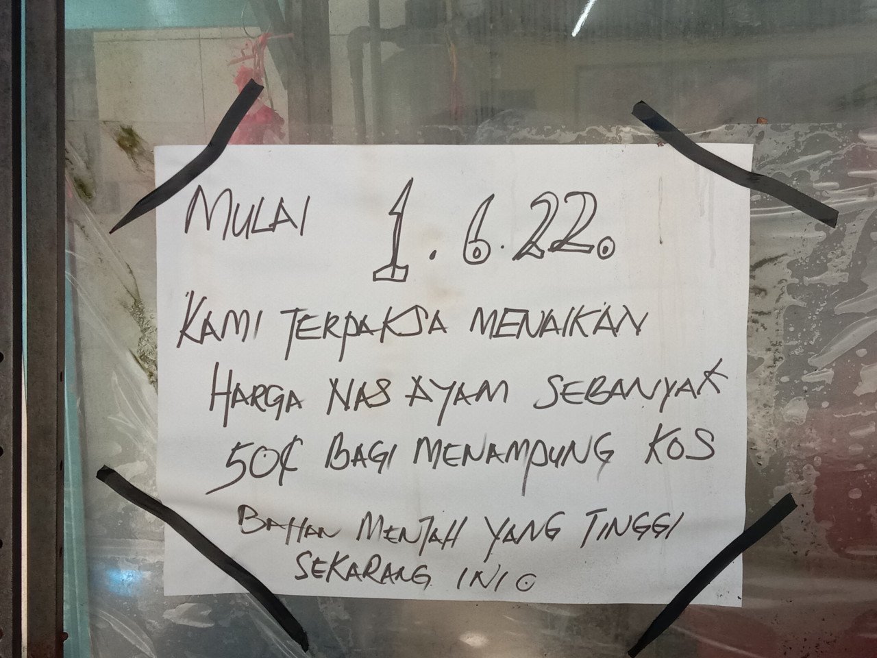 Notis ditampal disebuah gerai makan memberitahu pelanggan tentang kenaikkan harga nasi ayam. - Gambar oleh Qistina Nadia