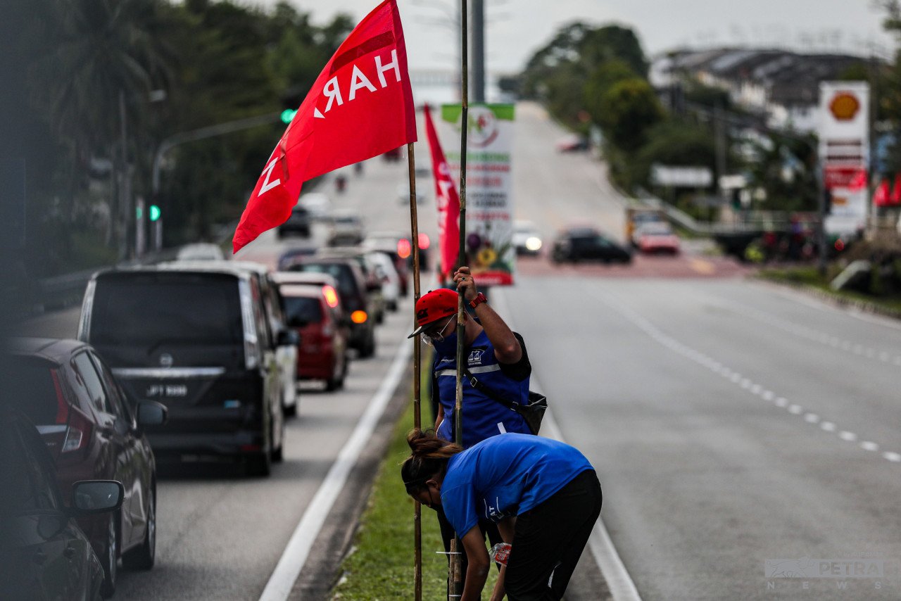 Dua petugas parti BN memacak bendera di kawasan DUN Johor Jaya.