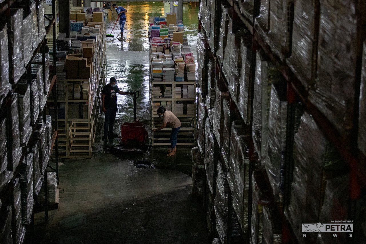 Pekerja BookXcess membersihkan gudang buku berkenaan susulan banjir, baru-baru ini. - Gambar Sadiq Asyraf