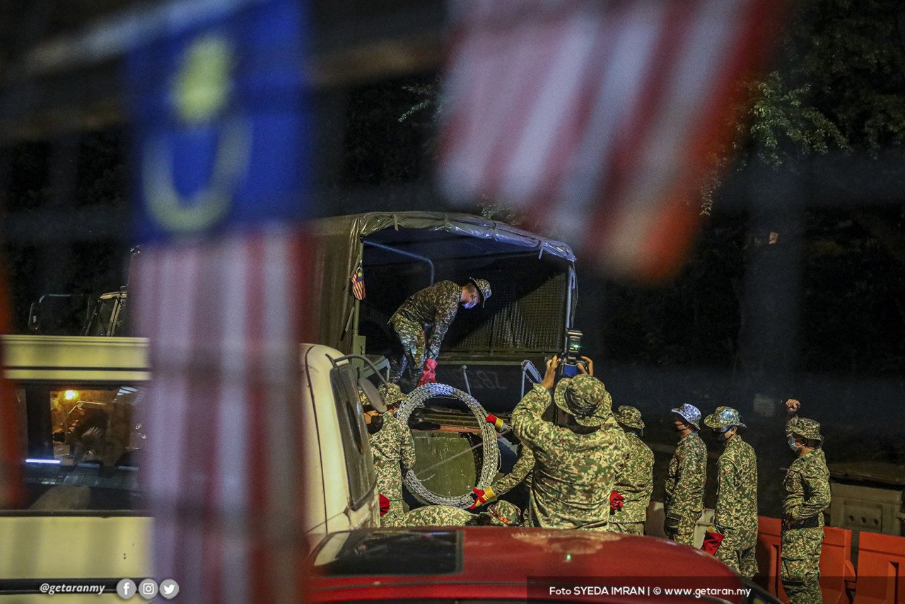 Anggota tentera memunggah kawat berduri turun dari lori untuk dipasang di sekeliling kawasan Pangsapuri Permai.