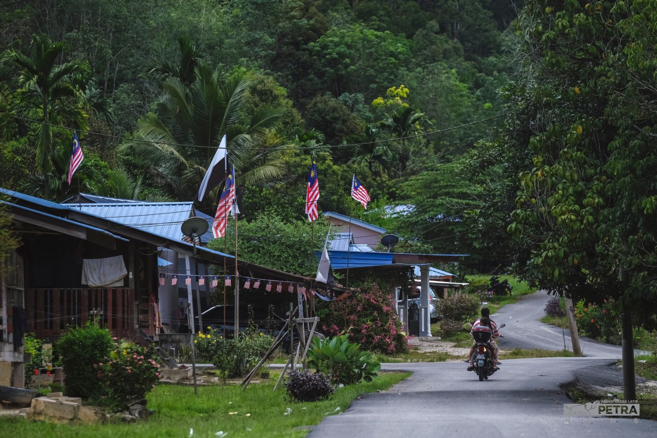 Kelihatan penduduk Perkampungan Orang Asli Kg Chinta Manis memasang Jalur Gemilang di rumah bagi menyambut Hari Kemerdekaan. - Gambar oleh Abdul Razak Latif
