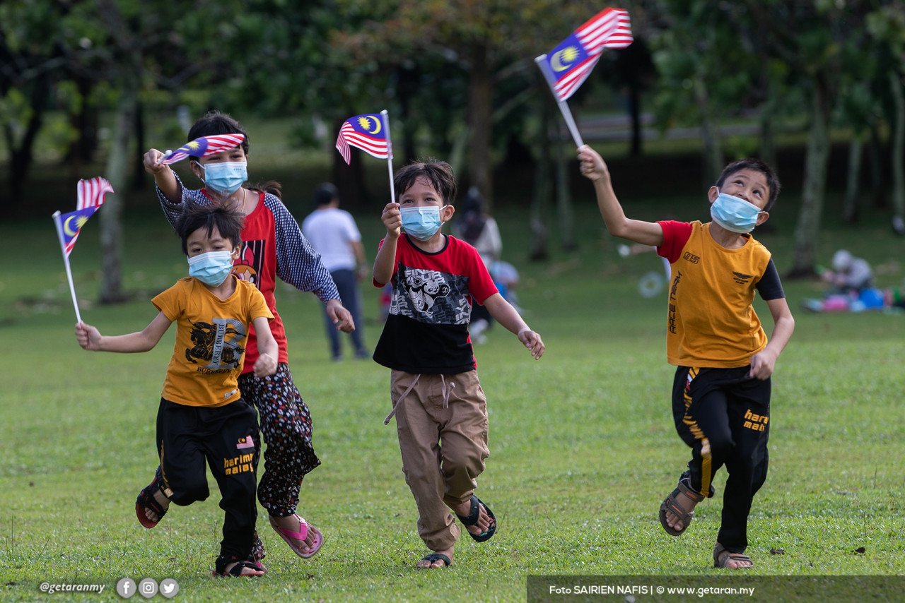 Sekumpulan kanak-kanak berlarian sambil mengibarkan Jalur Gemilang. - Gambar oleh Sairien Nafis