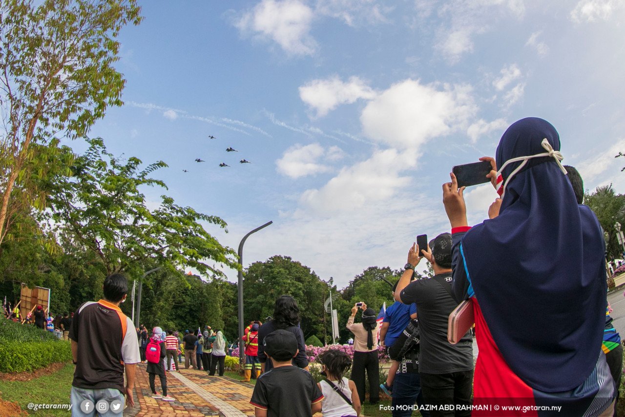Orang ramai mengambil kesempatan merakamkan aksi pesawat TUDM yang membuat persembahan semasa Sambutan Hari Kemerdekaan di Putrajaya. - Gambar oleh Azim Rahman